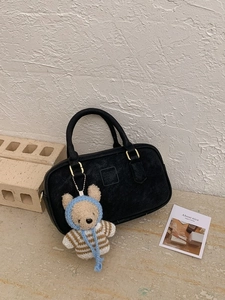 Sac à main noir mat minimaliste avec breloque ours sur un fond en pierre élégant