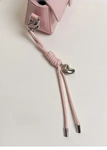 Dettaglio borsa rosa con cordino intrecciato e ciondolo a cuore in argento