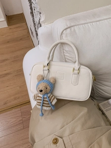 Sac à main Boston beige avec breloque ours sur canapé, style minimaliste chic