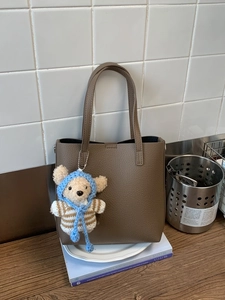 Dark brown pebble leather bucket bag with cute plush bear charm for daily commuting