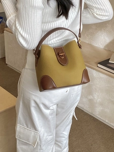 Women's minimalist bucket bag in yellow-green and brown leather with metal twist lock