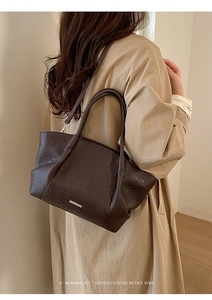 Détail d'un sac cabas marron foncé en cuir froissé avec plaque métallique minimaliste