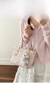Détail du motif nœud rose sur sac seau beige avec joli porte-clés en peluche ours