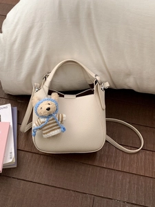 Chic beige bucket bag with cute teddy bear pendant and thin shoulder strap