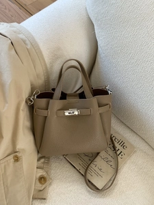 Sac seau en cuir marron avec fermoir tournant argenté sur fond de tissu blanc épuré
