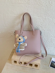 Pink lychee grain leather bucket bag with a cute bear charm for daily commuting