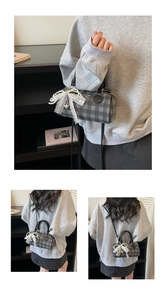 Détail du sac baril à carreaux gris avec nœud en dentelle et pendentif cœur