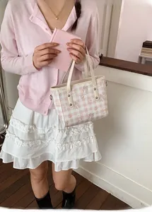 Détail d'un sac cabas à carreaux roses avec imprimés d'ours tenu par un mannequin
