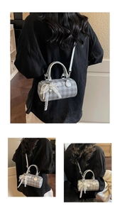 Détail du sac cylindre avec motif à carreaux gris, nœud en dentelle et perle décorative