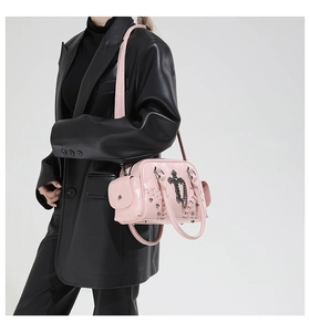 Détail du sac à main punk rose avec pendentif croix gothique, chaînes noires et rivets