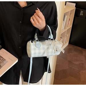 Détail du sac Boston à carreaux bleus avec nœud en dentelle, perles et cœur argenté