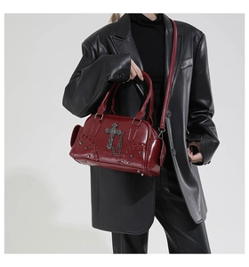 Détail d'un sac à bandoulière gothique rouge foncé avec croix en métal et rivets