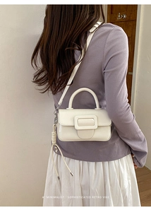 Elegante borsa a mano in pelle bianca con maxi fibbia su modella con outfit minimalista