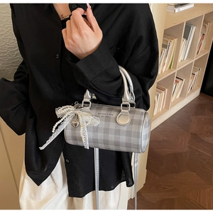 Détail du sac cylindrique à carreaux argenté avec nœud en dentelle perle et pendentif cœur