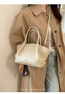 Gros plan d'un sac cabas crème rétro avec texture cuir froissé et plaque métallique