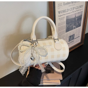 Détail du sac Boston à carreaux avec nœud en dentelle et pendentif en perles élégant