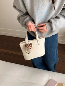 Chic beige lychee leather tote bag with a cute plush bear charm for a stylish look