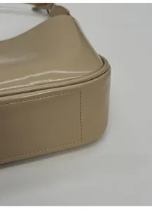 Makroansicht des breiten Bodens und der präzisen Nähte der beigen Leder-Baguette-Tasche