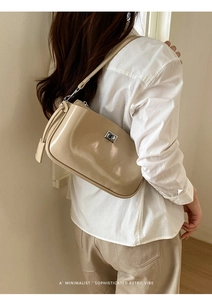 Detail einer schicken beigen Lackleder-Achseltasche mit silberner Schnalle an der Seite