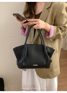 Détail du sac cabas noir avec texture plissée rétro et logo argenté sur tenue chic