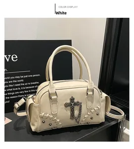 Détail du sac Boston blanc avec pendentif croix, décor de chaîne et coutures