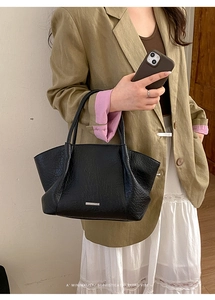 Détail montrant la texture du cuir plissé et le logo métallique sur ce sac fourre-tout