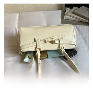 Spacious interior of the cream leather shoulder bag showing smartphone and makeup items