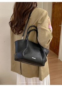 Détail d'un grand sac cabas noir en cuir vintage avec logo porté par un mannequin