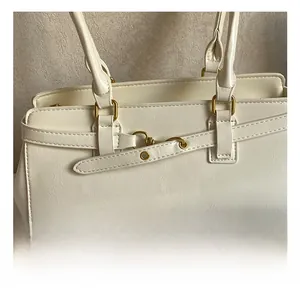 Close-up of premium cream faux leather handbag featuring polished gold hardware accents