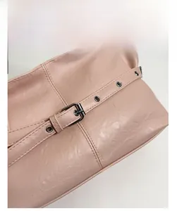 Détail macro de la texture du cuir plissé et de la boucle argentée sur le sac cabas rose