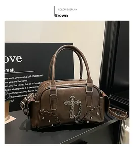 Détail macro du sac en cuir marron avec croix métallique gothique et clous décoratifs