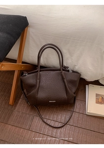 Détail de la texture du cuir marron foncé et des coutures sur un cabas vintage