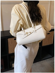 Detailed view of a white vintage leather underarm bag with gold metal buckle hardware