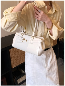 Detail of white glossy shoulder bag with gold hardware and stylish double handles