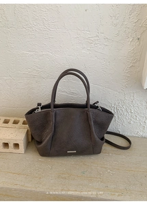 Détail du cabas en cuir marron foncé avec texture grainée et plaque logo argentée