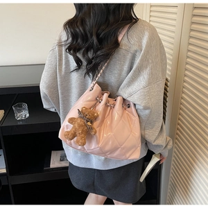 Detailed close-up of pink quilted bucket bag with silver chain and plush bear charm decoration