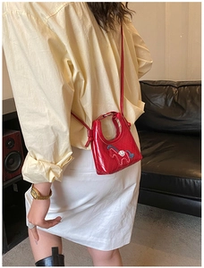 Close-up of a mini red quilted bag with a horse motif shown on a model's outfit