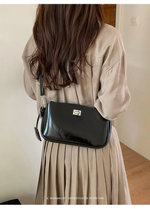 Detail einer minimalistischen schwarzen Lackleder-Schultertasche mit silbernem Drehverschluss