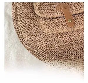 Gros plan sur un sac selle en paille tressée avec lanière en cuir et fermoir en bronze