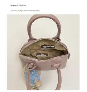 Internal view of pink shell bag showing main compartment, zipper pocket and bear charm