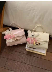 Close-up of pink and beige bucket bags with gold locks and cute plush bunny charms