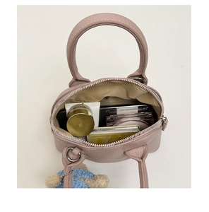 Top view of pink leather handbag showing spacious interior for makeup and bear charm