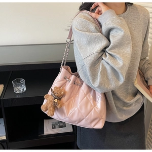 Detail of pink quilted shoulder bag with chain strap and cute teddy bear charm