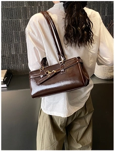 Detail of dark brown glossy leather handbag with elegant gold metal buckle and vintage texture