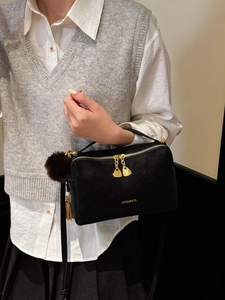 Schicke schwarze Handtasche mit goldenen Beschlägen und Anhänger am Modell getragen