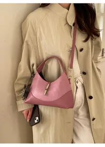 Mauve leather hobo bag with silver piston clasp shown on model wearing a trench coat