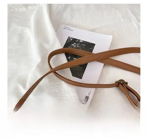 Détail de la bandoulière réglable en cuir marron avec une boucle en métal bronze