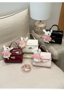 Detail view of stylish small bucket bags in four colors with cute rabbit charms and straps