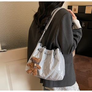 Detail of quilted leather bucket bag with silver chain strap and plush bear charm