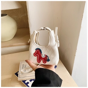 Detailed close-up of a white quilted mini bag with horse embroidery in a home setting